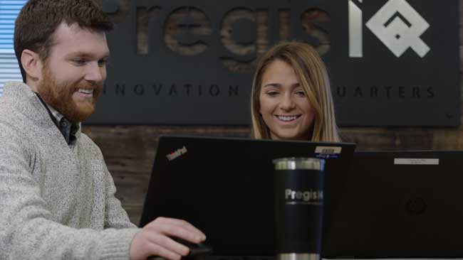 Two colleagues collaborating on laptops in the Pregis IQ office.